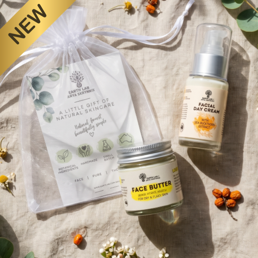 Earth Lab Natural Skincare Gift Set featuring Face Butter and Sea Buckthorn Facial Day Cream, presented in a white organza gift bag with a botanical gift card, surrounded by fresh flowers, eucalyptus leaves and sea buckthorn berries in soft natural light.